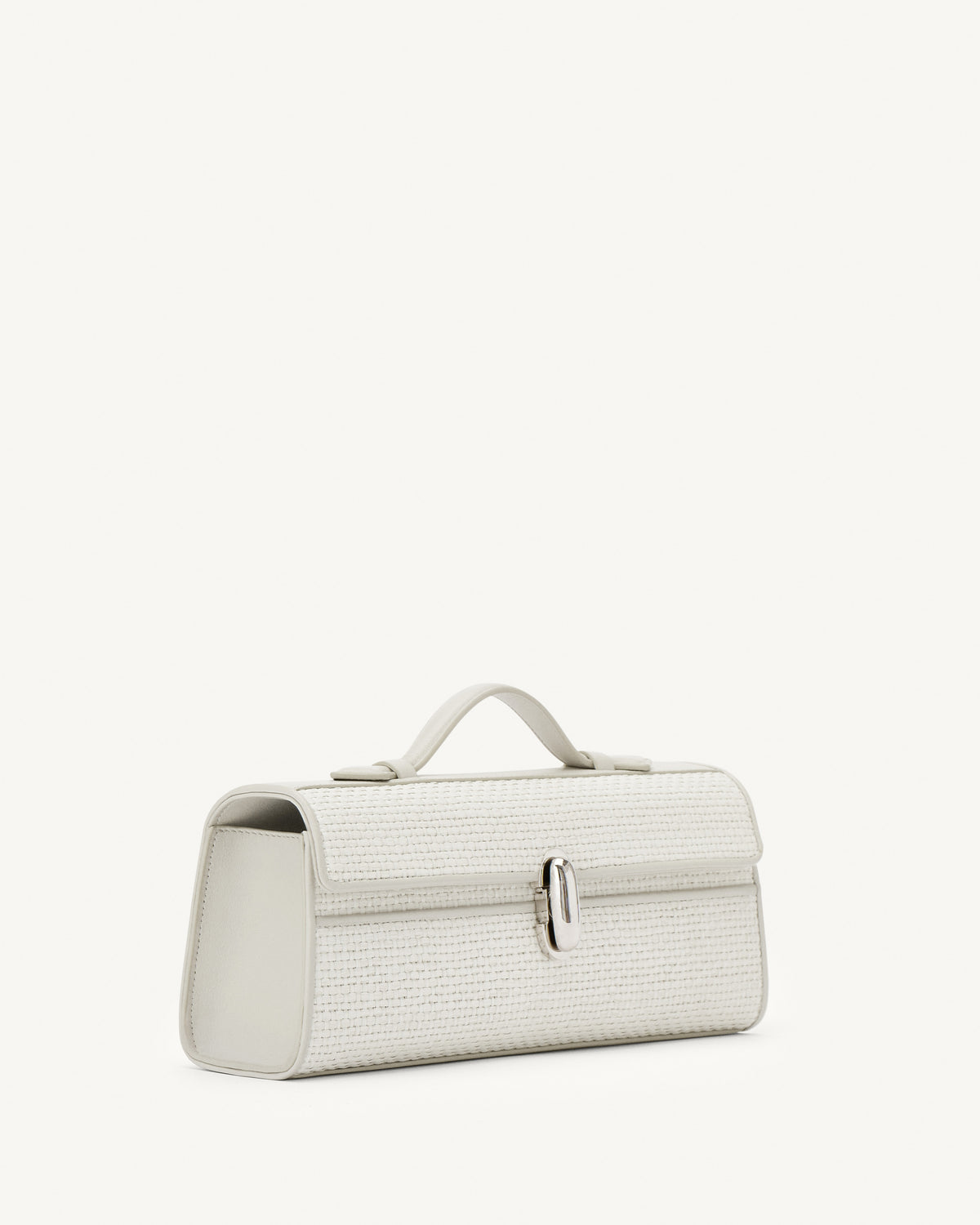 side view of an ivory raffia bag with silver hardware on a white background