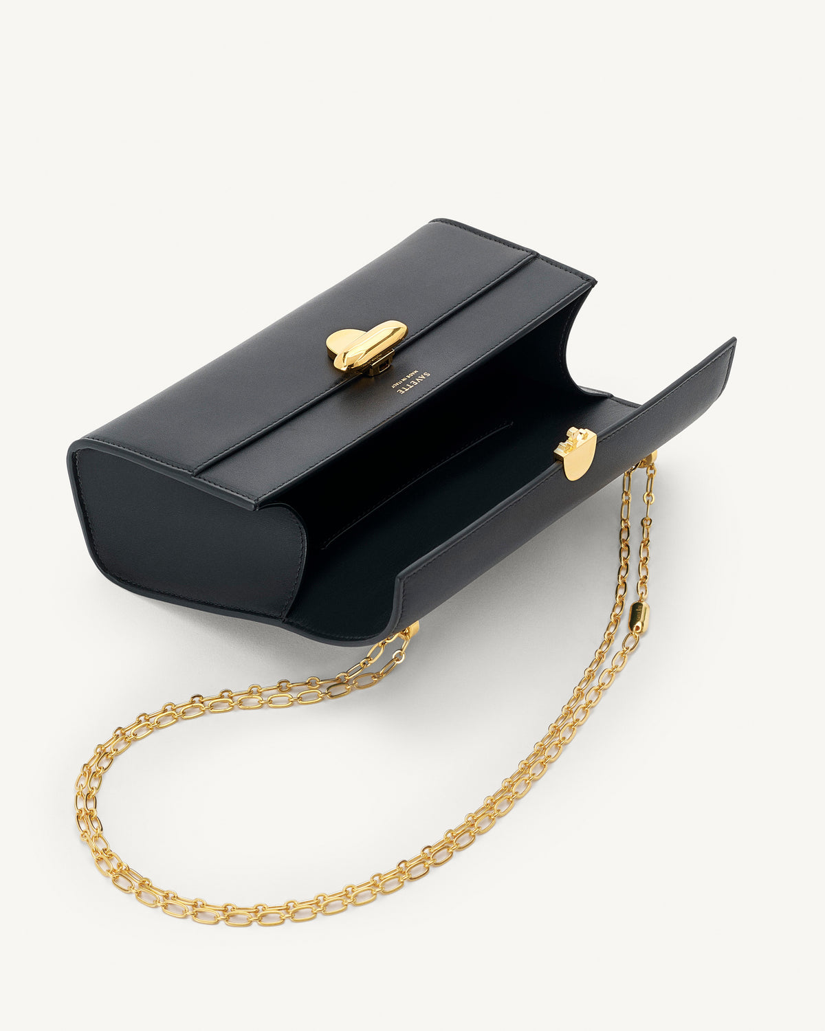 interior view of black bag with gold clasp and gold chain on a white background