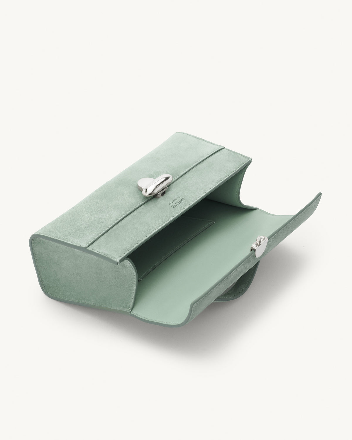 interior view of mist green suede bag with silver clasp on a white background