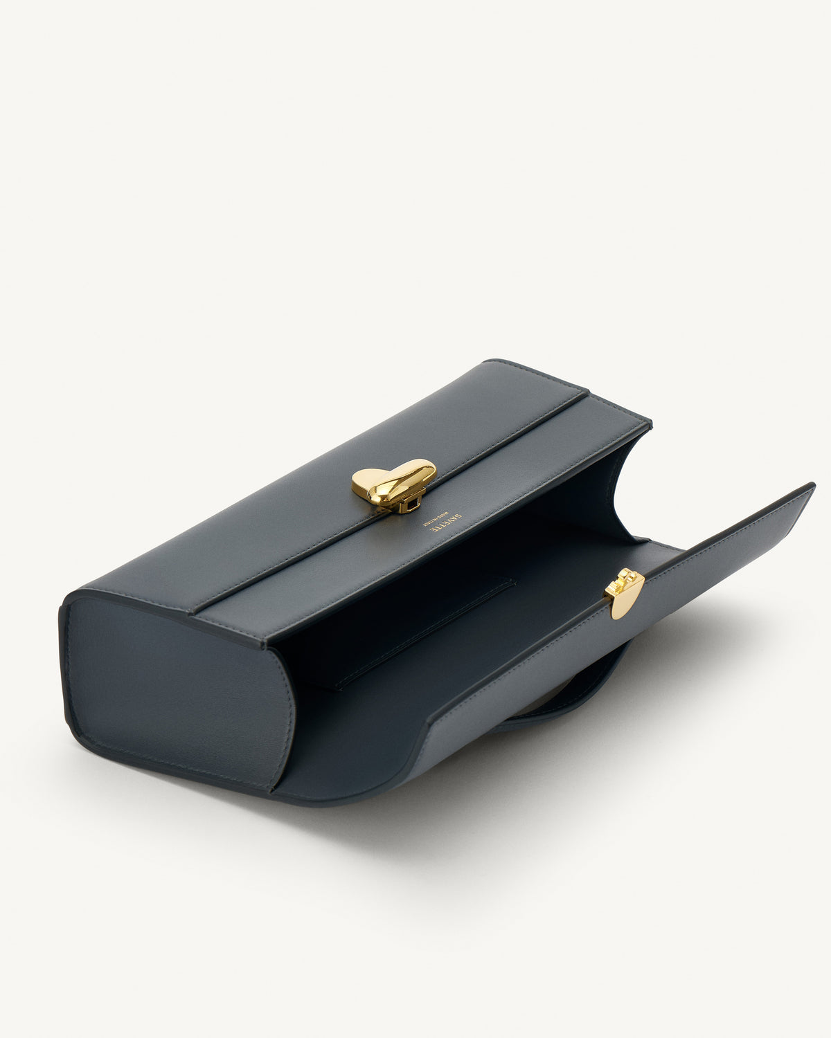 interior view of a storm blue leather bag with a gold clasp on a white background