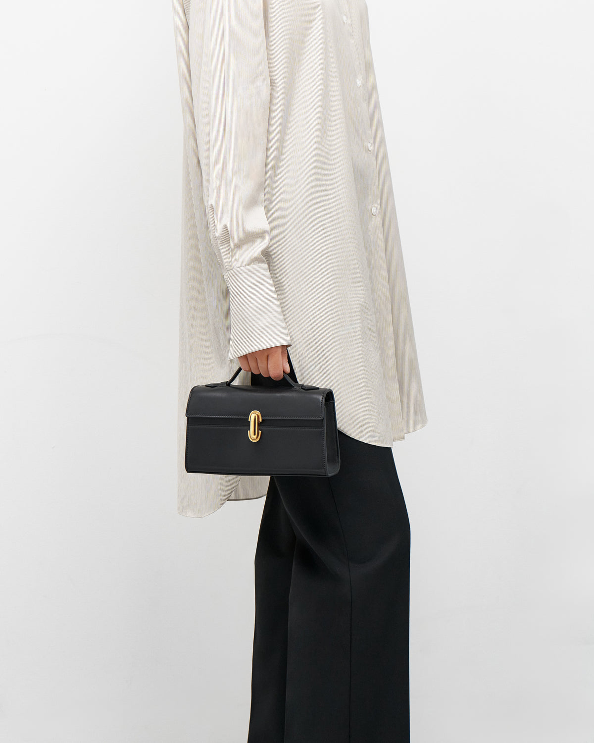 on model view of a black leather bag with a gold clasp on a white background
