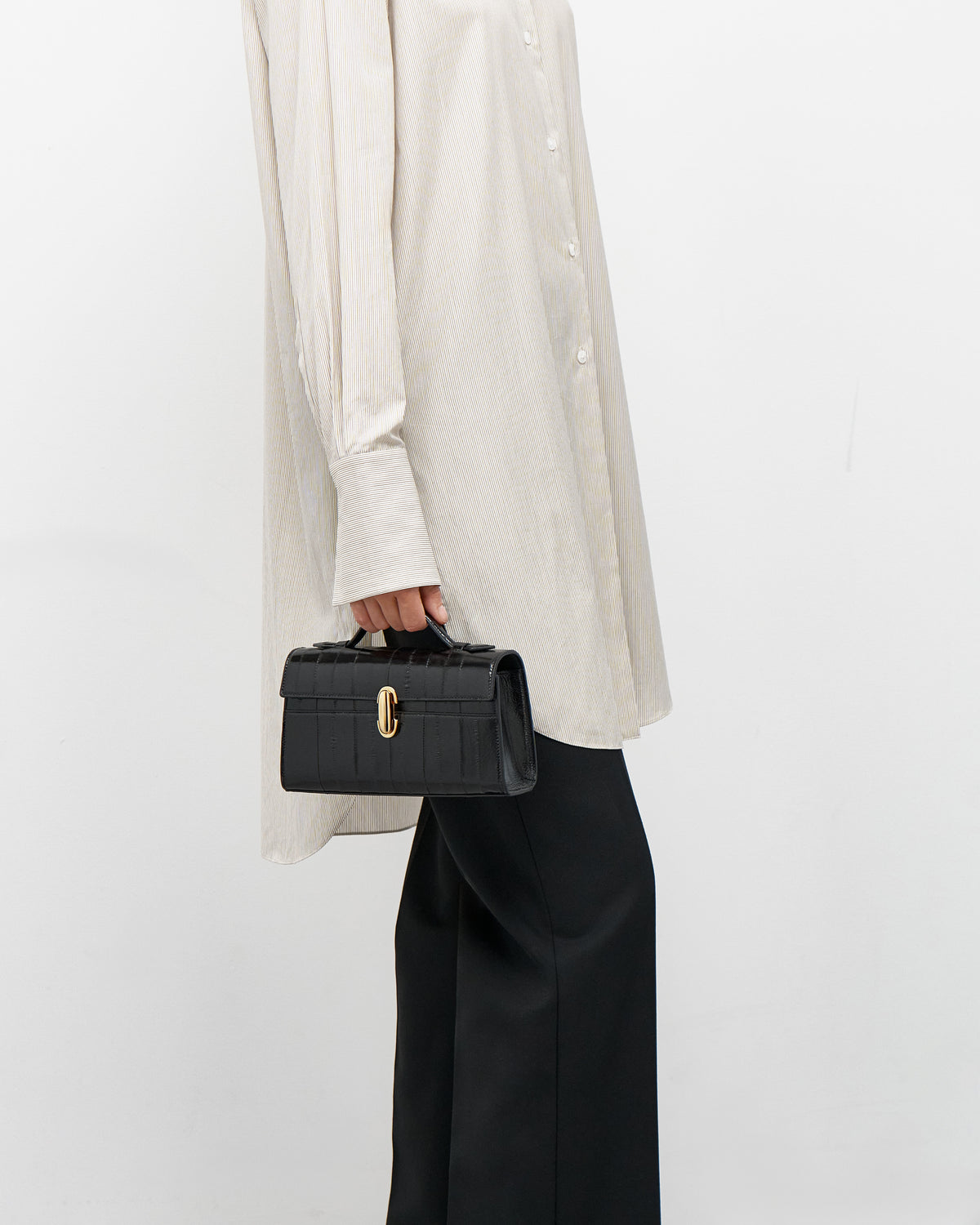 on model view of a black eel bag with a gold clasp on a white background