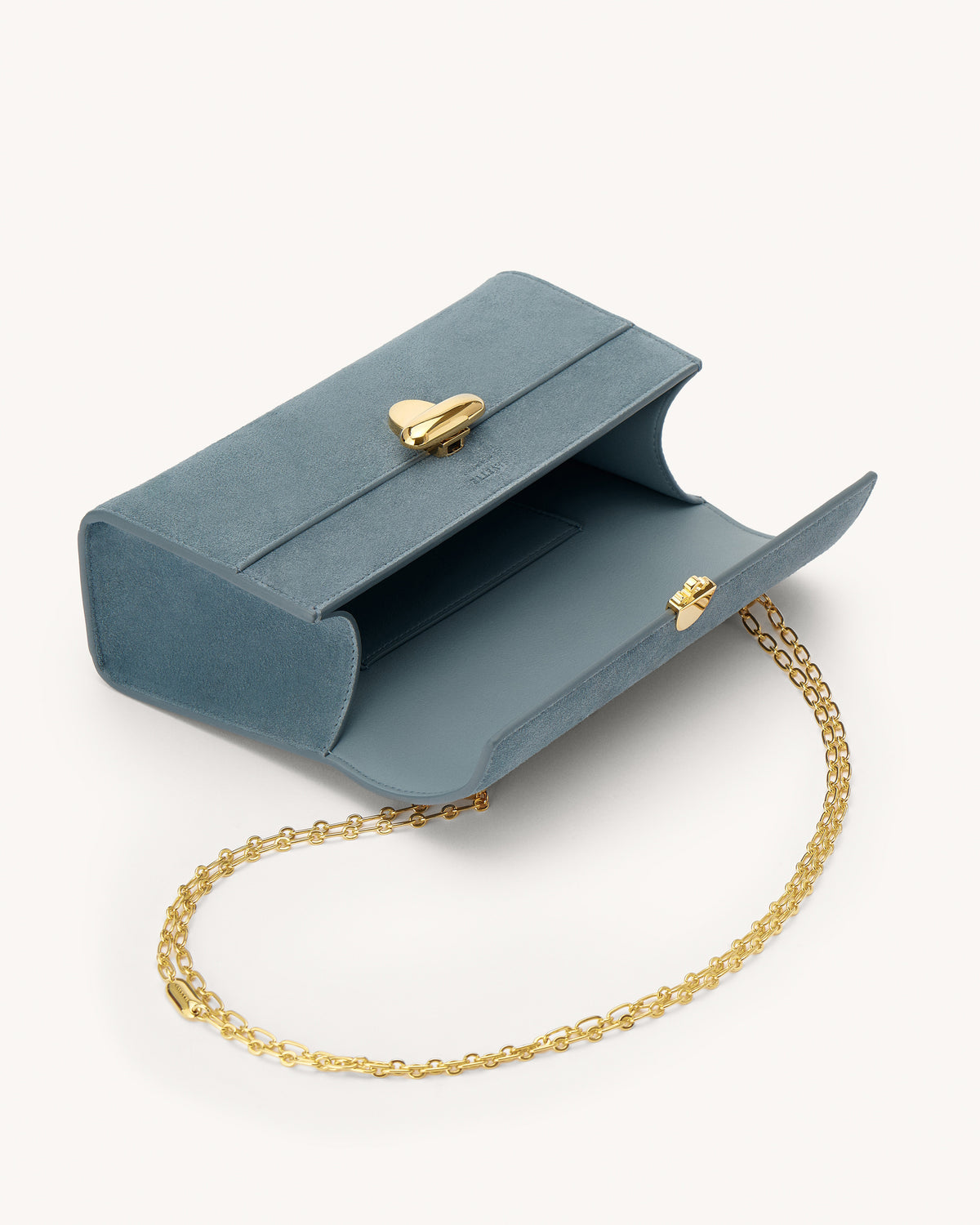 interior view of a denim blue suede bag with a gold clasp and gold chain on a white background