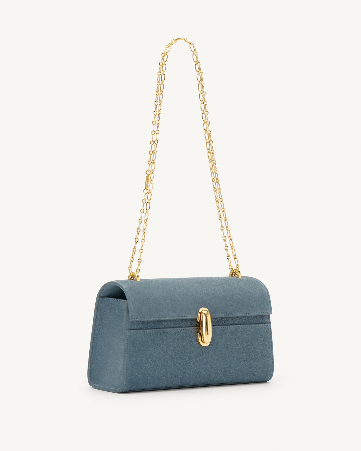 side view of a denim blue suede bag with a gold clasp and gold chain on a white background
