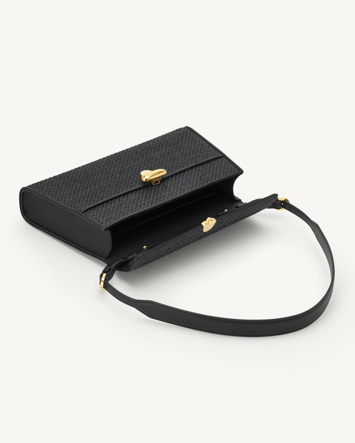 interior view of a black raffia bag with leather trim with a gold clasp on a white background