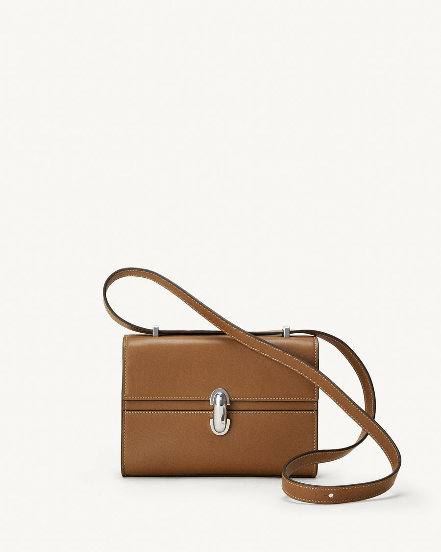 front view of a saddle brown leather bag with a silver clasp on a white background