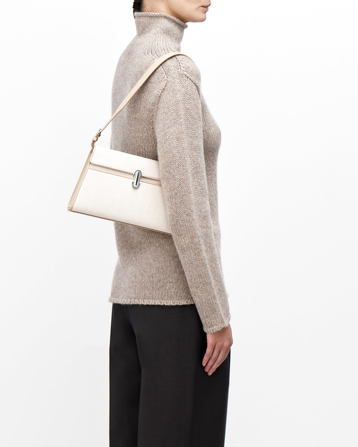 On model view of white canvas shoulder handbag with a silver chain strap on a white background