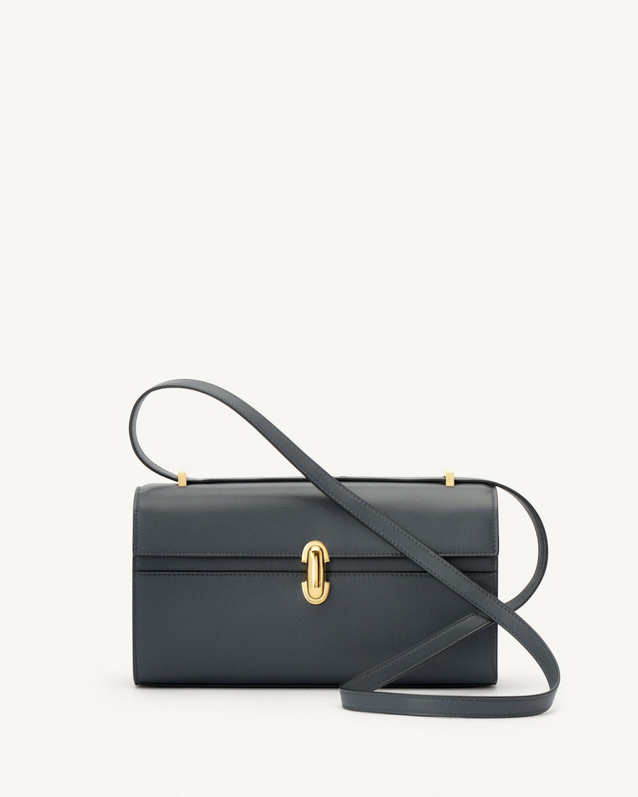 front view of a storm blue leather bag with a gold clasp on a white background