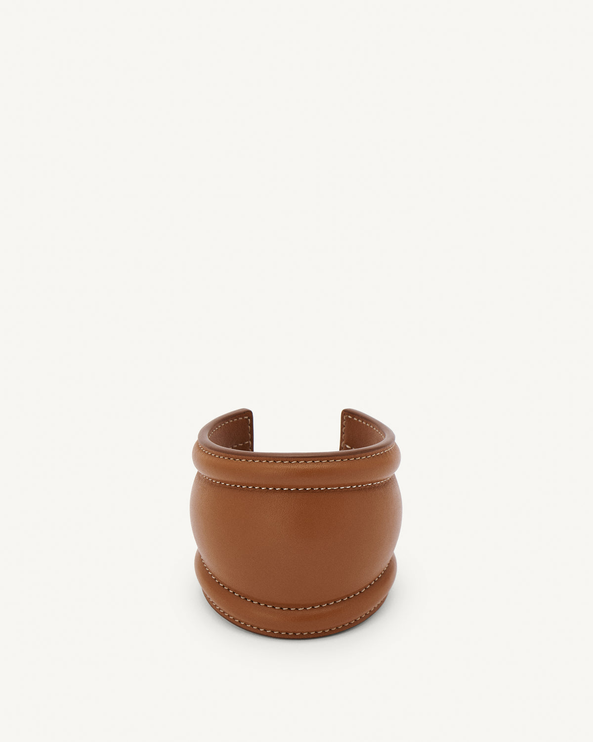 front view of a cognac brown leather cuff with white stitching on a white background 