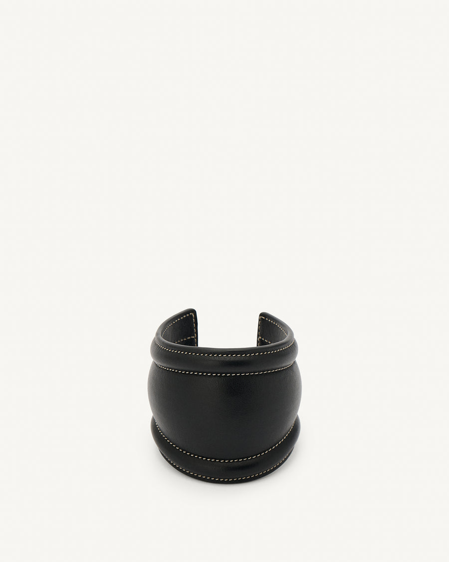 front view of a black leather cuff with white stitching on a white background