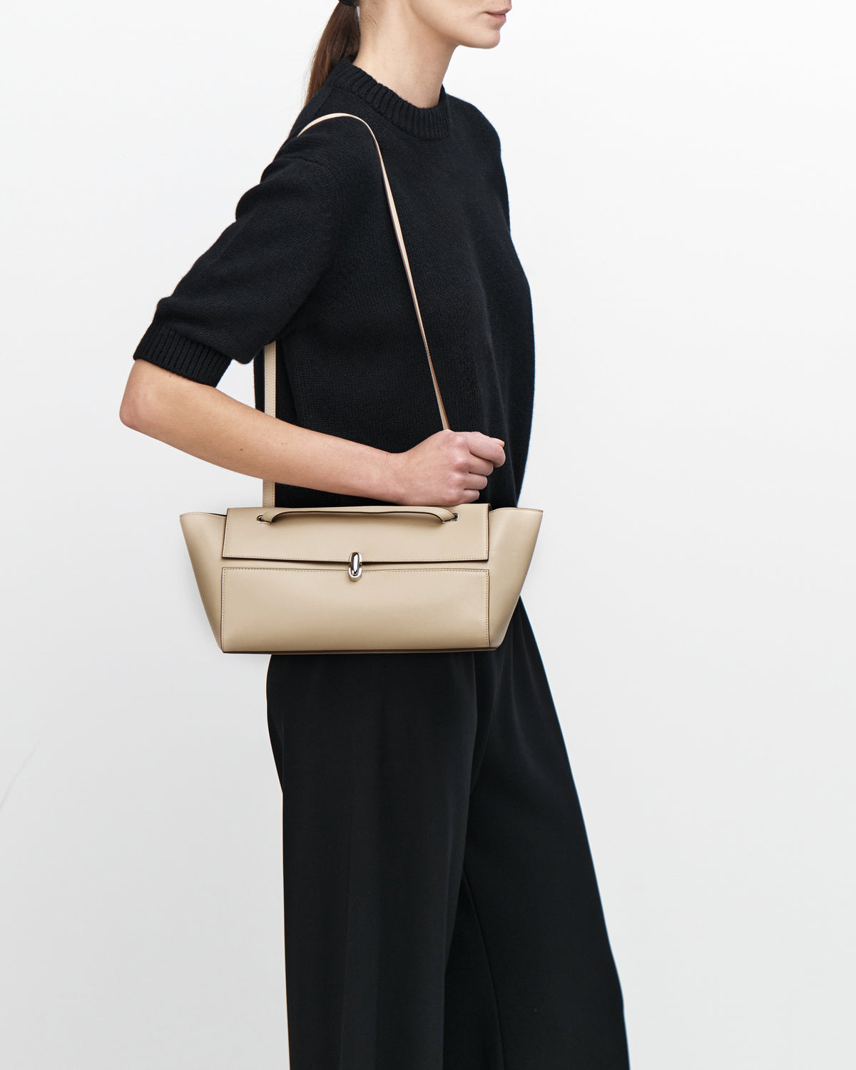 on model image of a bone beige leather bag with a silver clasp on a white background