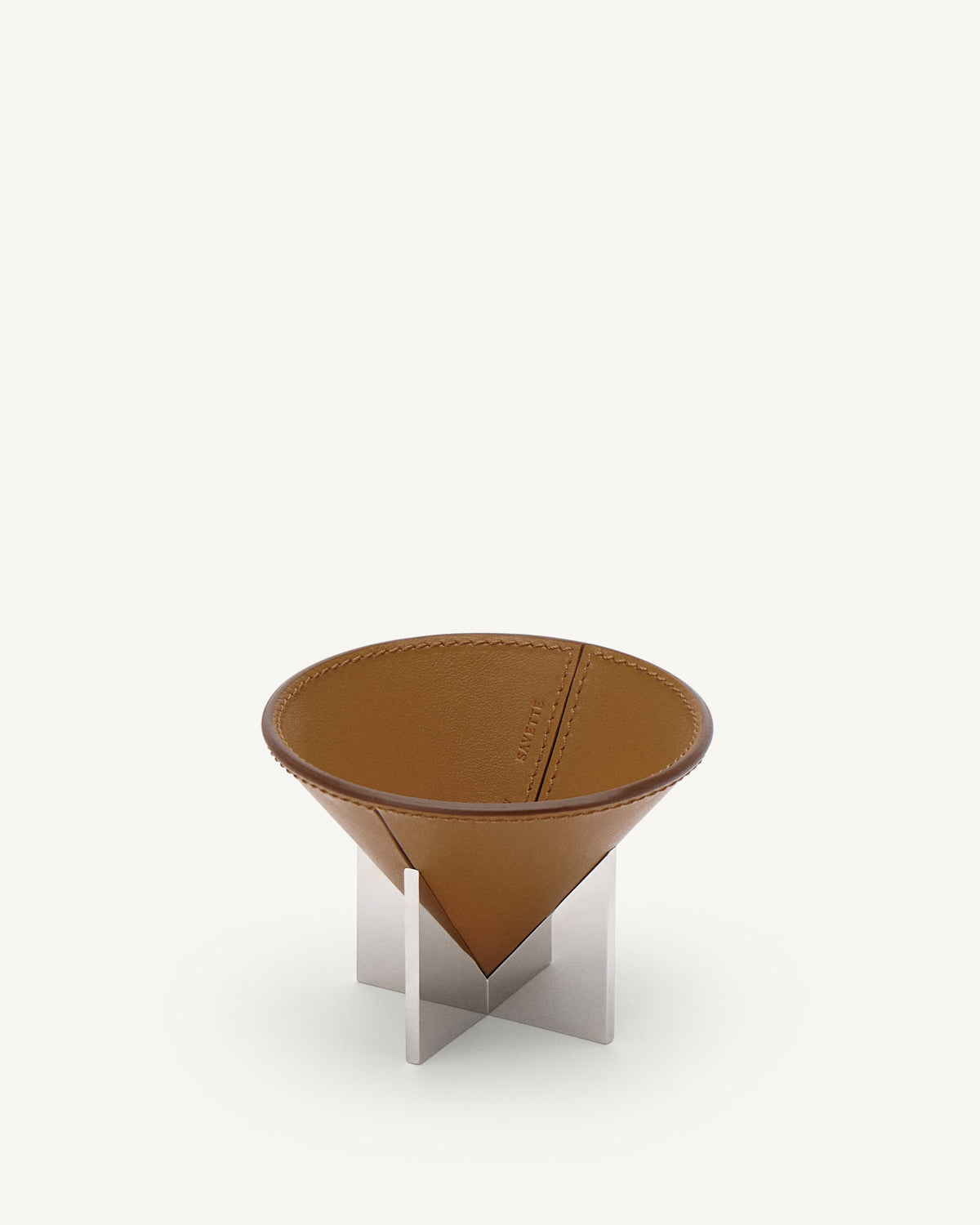 interior view of a saddle brown leather dish with silver metal feet on a white background