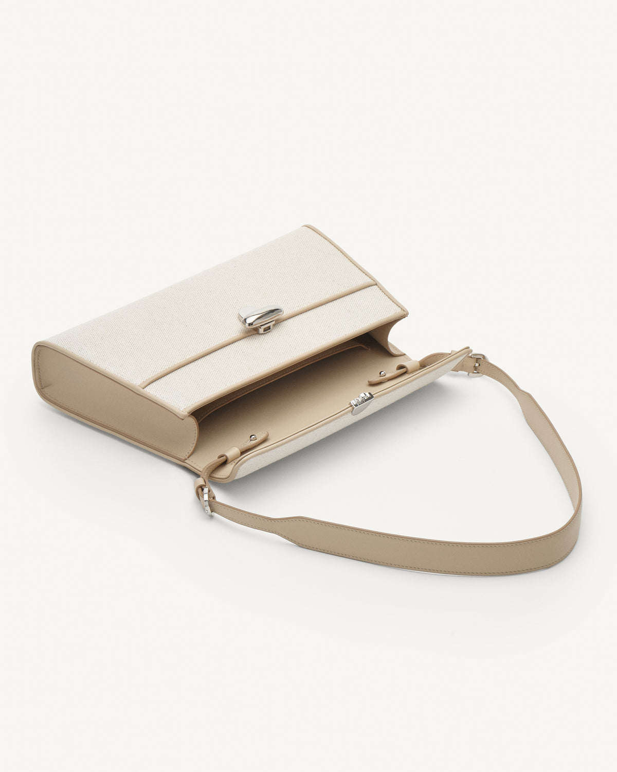 Inside view of white canvas shoulder handbag with a silver chain strap on a white background