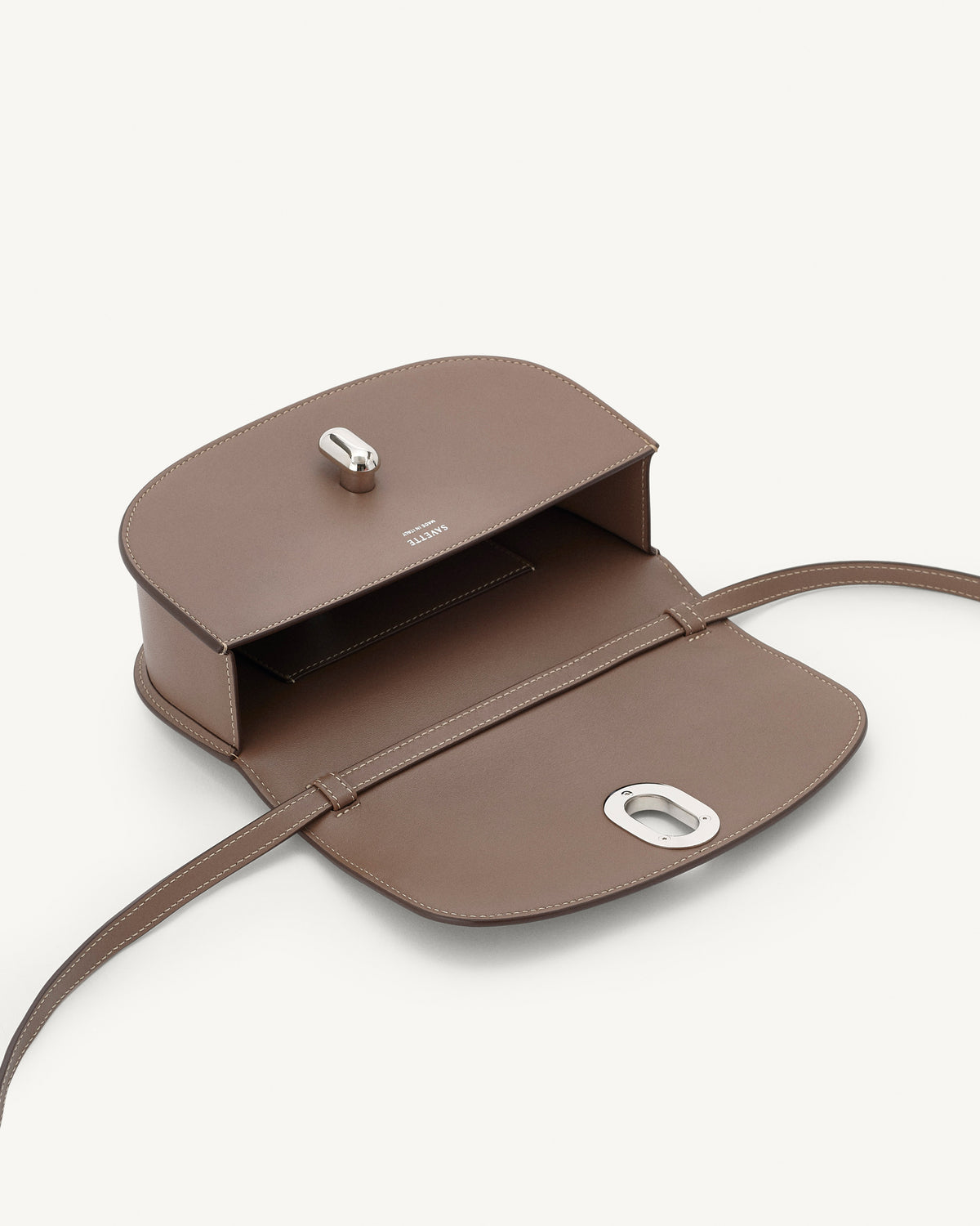 interior view of a taupe brown leather bag with silver hardware on a white background