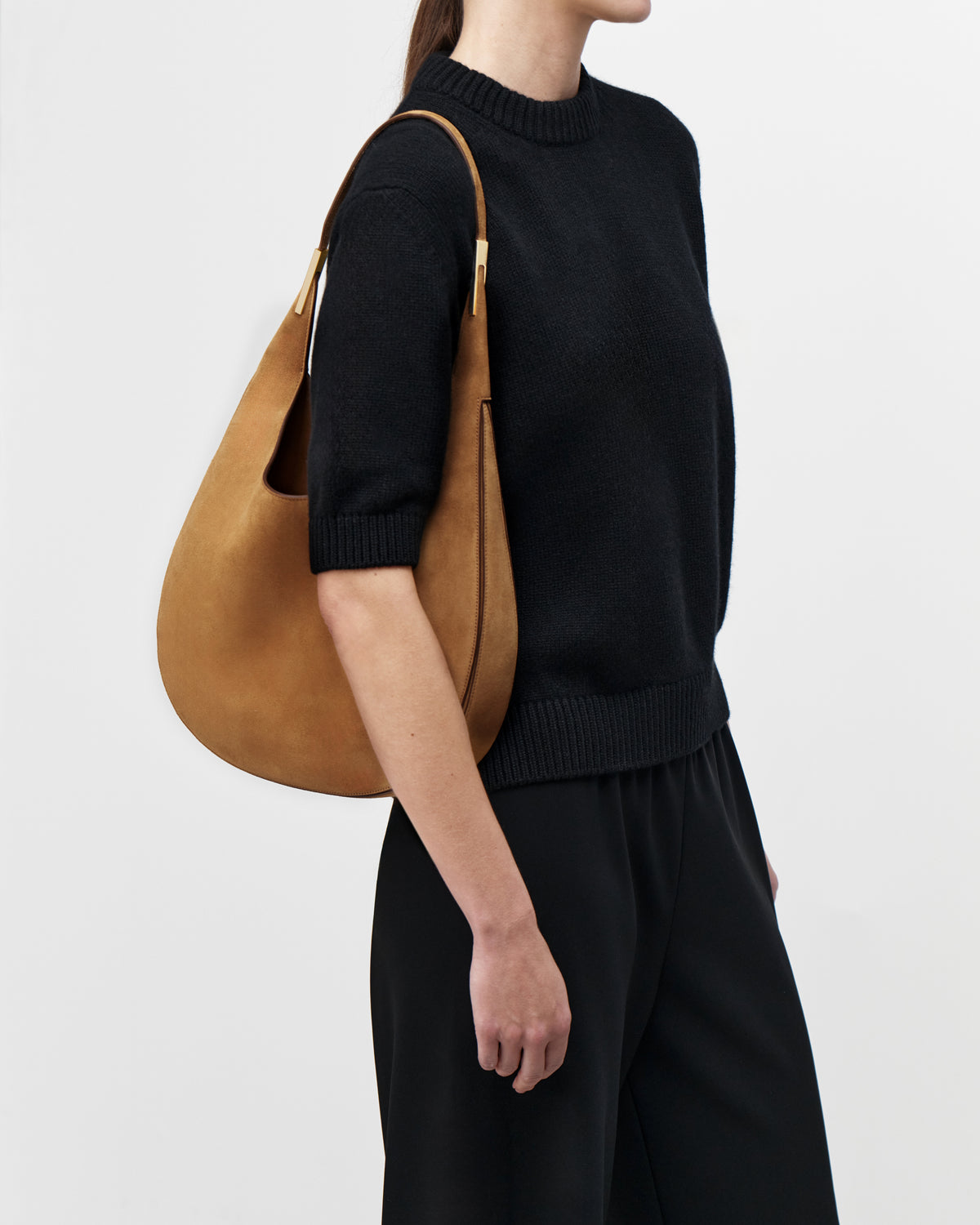 On model view of saddle suede tote bag with gold hardware on a white background