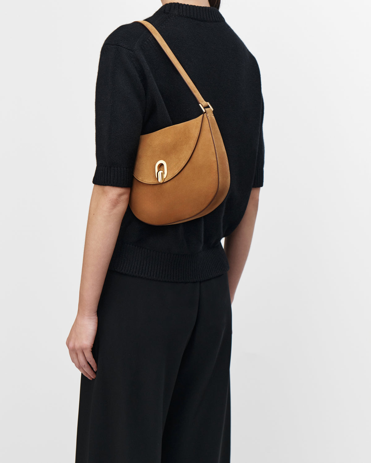 On model view saddle suede handbag with a gold clasp on a white background