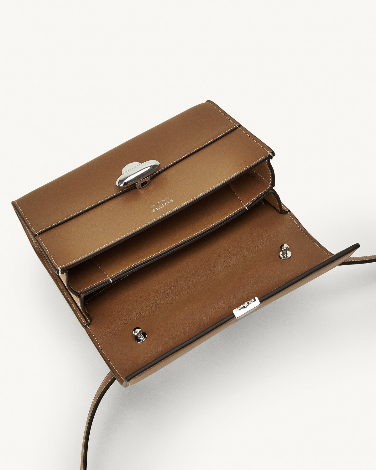 interior view of a saddle brown leather bag with a silver clasp on a white background