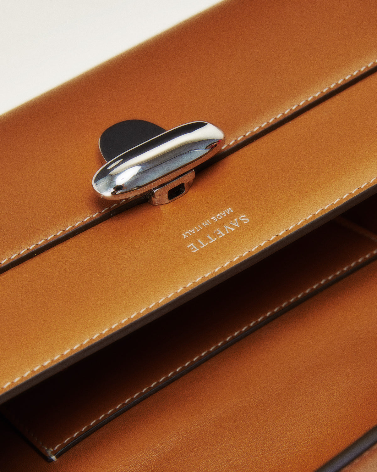 Editorial close up view of silver clasp on a maple brown bag