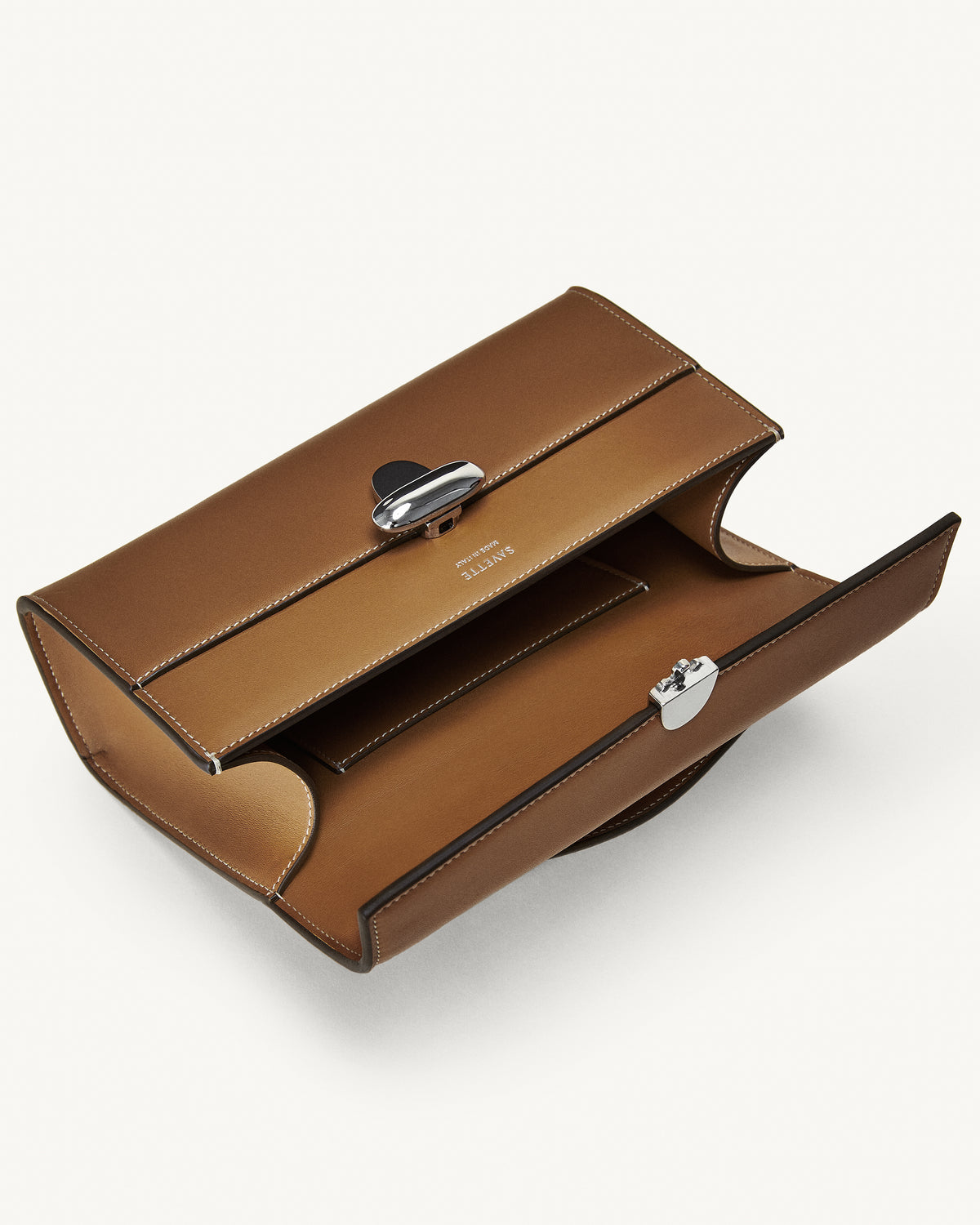 interior view of a saddle brown leather bag with a silver clasp on a white background