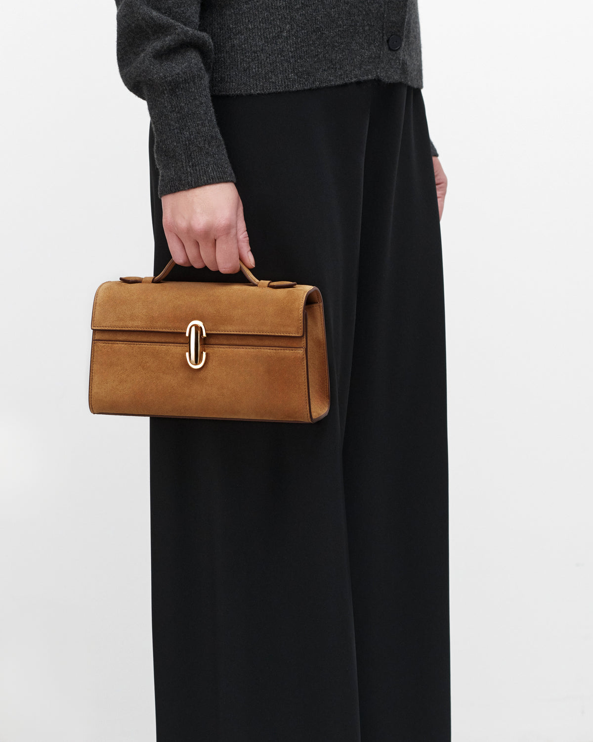 On model view of Saddle Suede leather handbag with a gold clasp on a white background