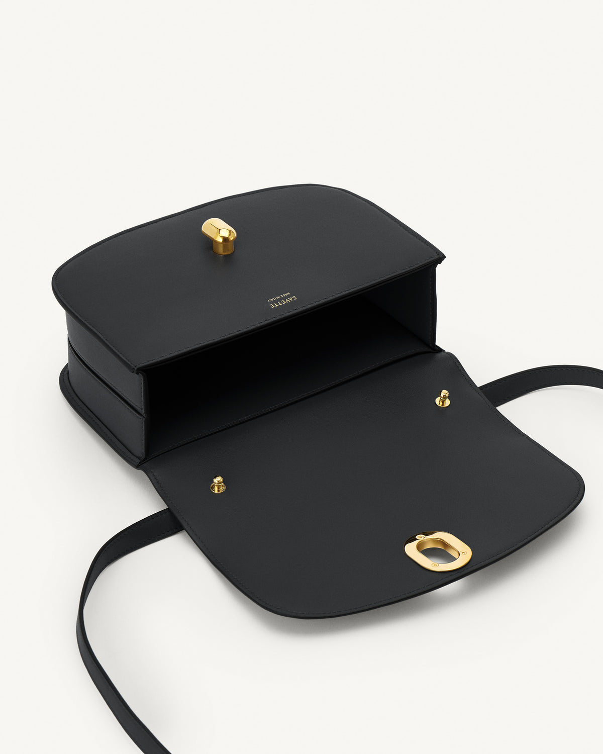 interior view of a black leather bag with gold hardware on a white background