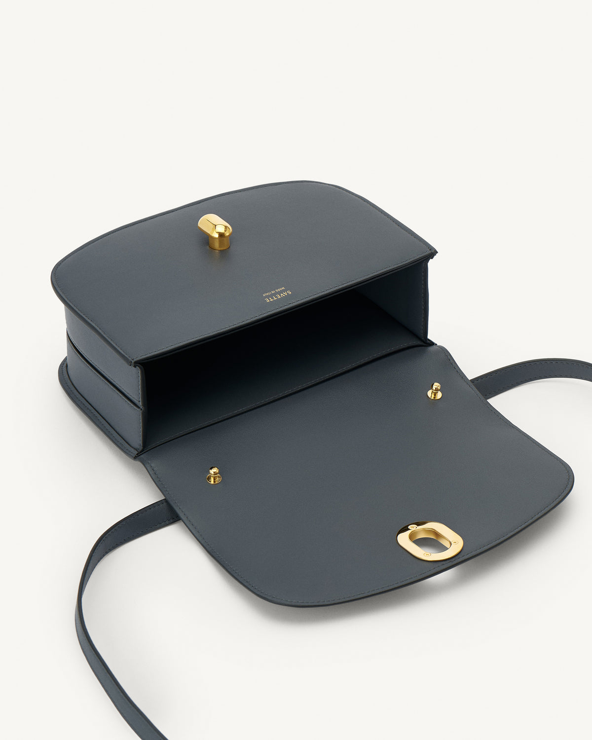 interior view of a storm blue leather bag with gold hardware on a white background