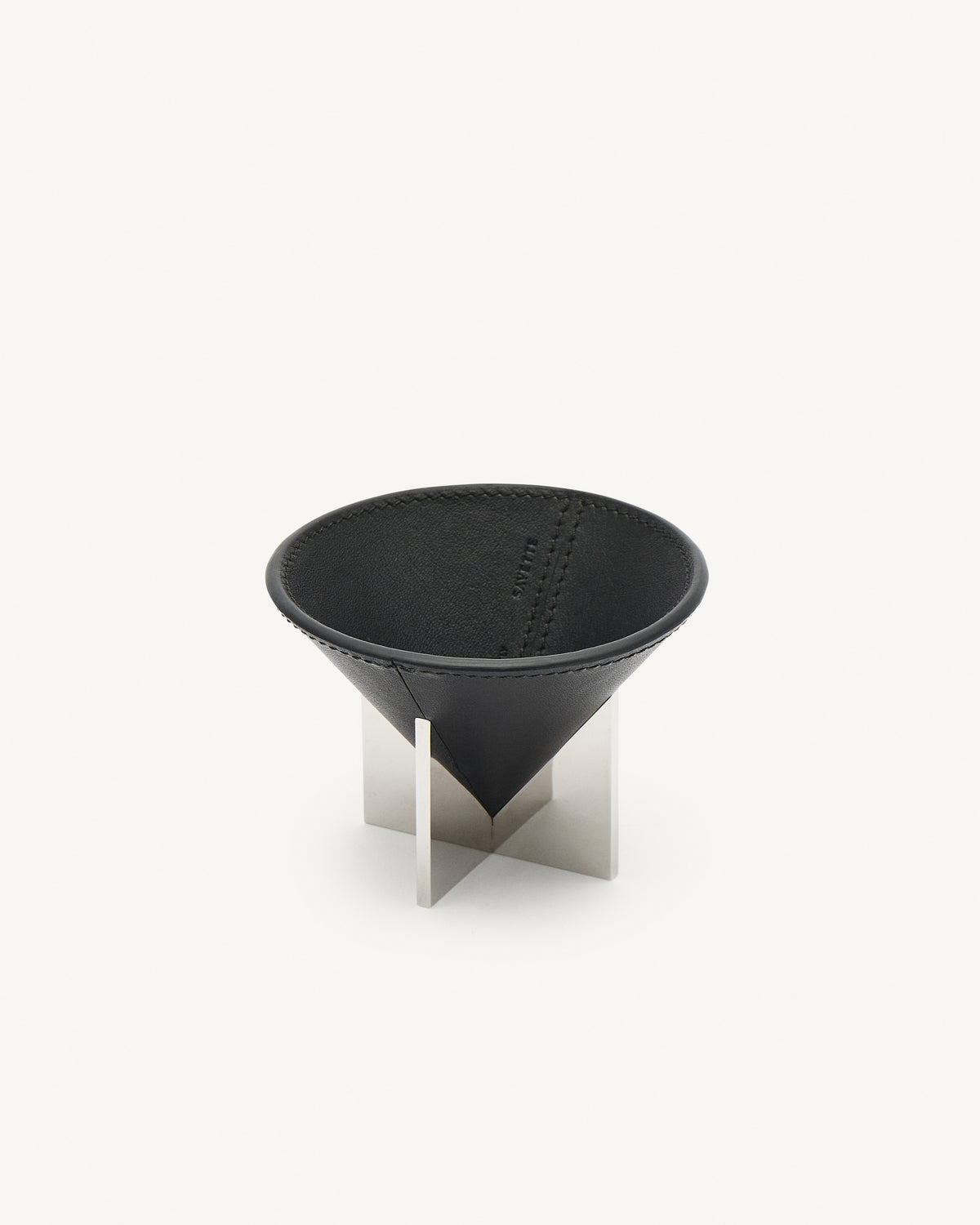 interior view of an ebony black leather dish with silver metal feet on a white background