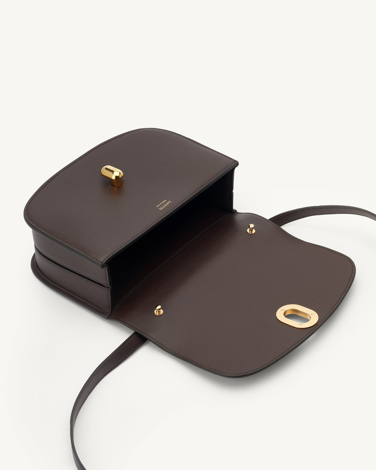 interior view of a coffee brown leather bag with gold hardware on a white background