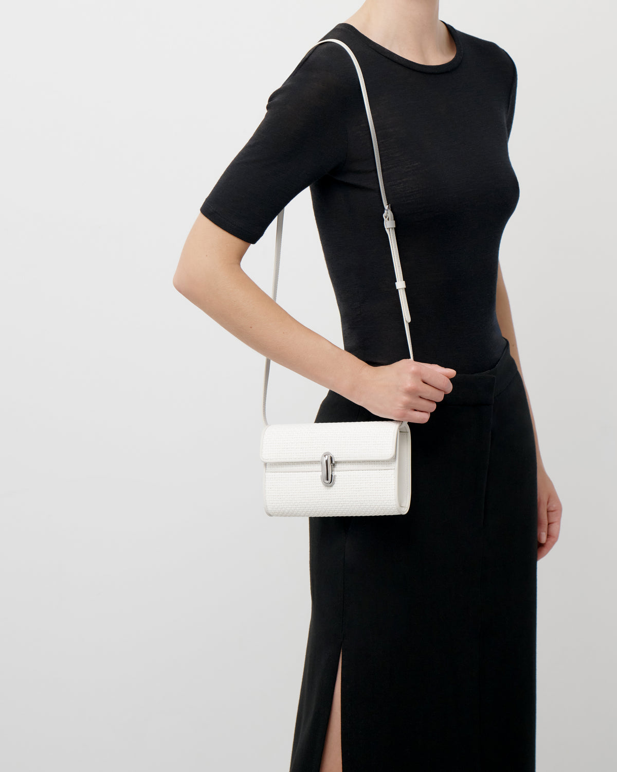 on model view of an ivory raffia bag with a silver clasp on a white background