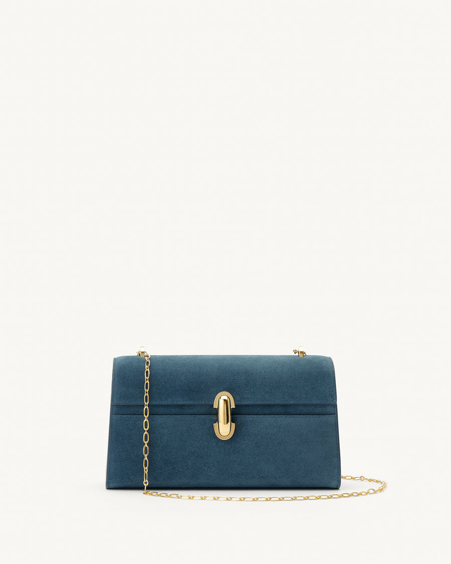 front view of a baltic blue suede handbag with a gold clasp and gold chain on a white background 