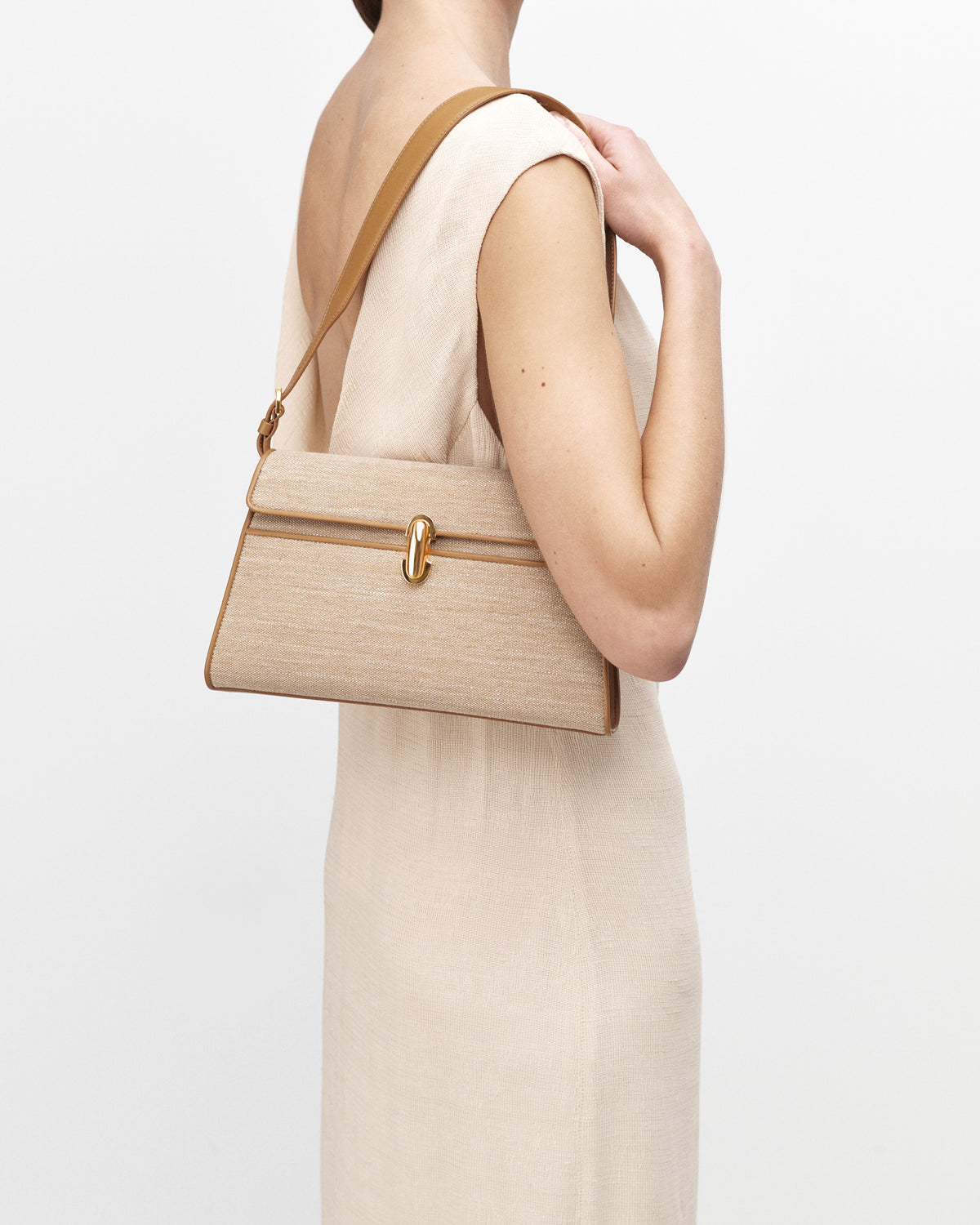 On model view of beige canvas shoulder bag with gold hardware