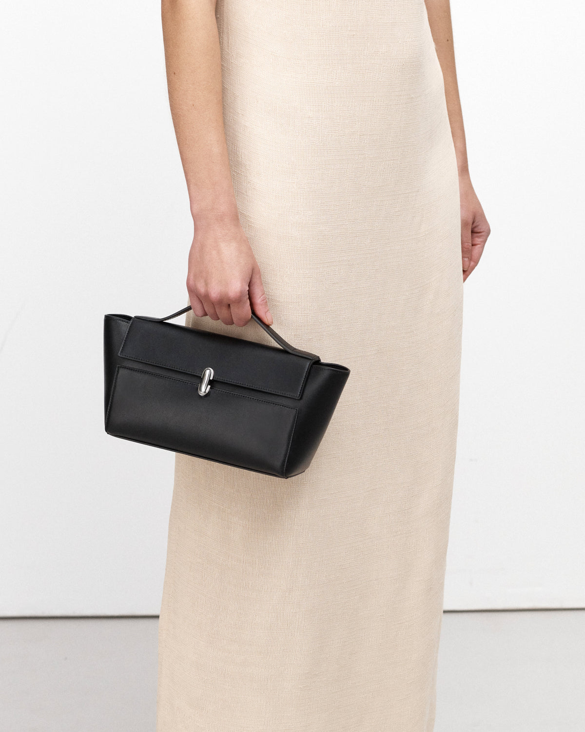 on model image of a black leather bag with a silver clasp on a white background