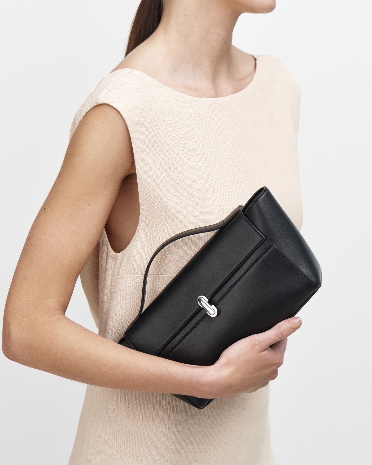 on model image of a black leather bag with a silver clasp on a white background