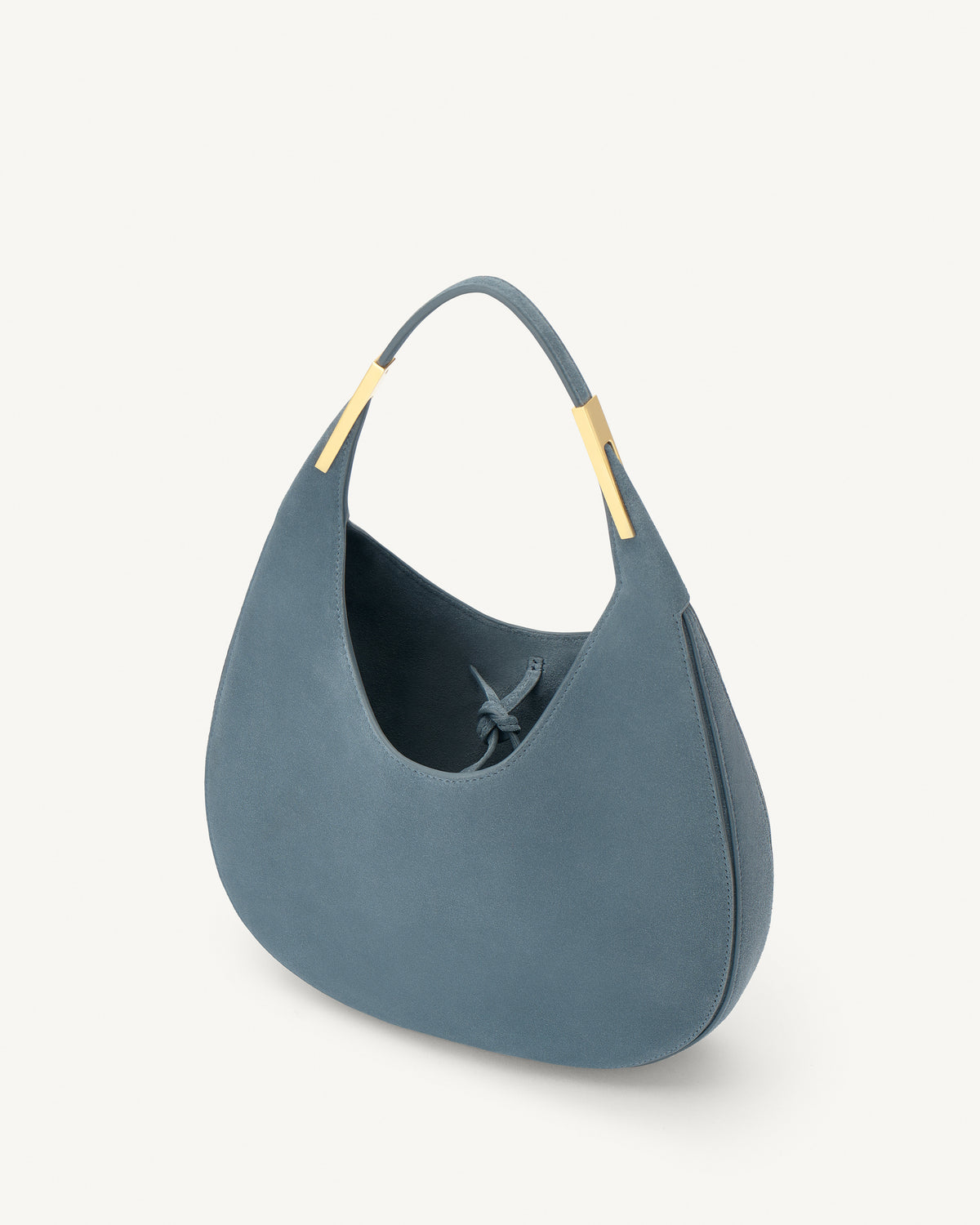 interior view of a denim blue suede bag with gold hardware on a white background