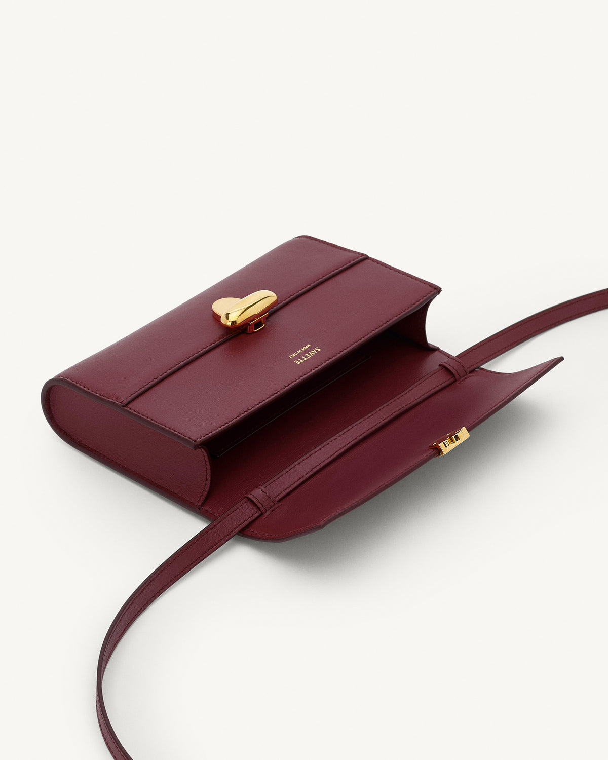 interior view of a wine red bag with gold clasp on a white background