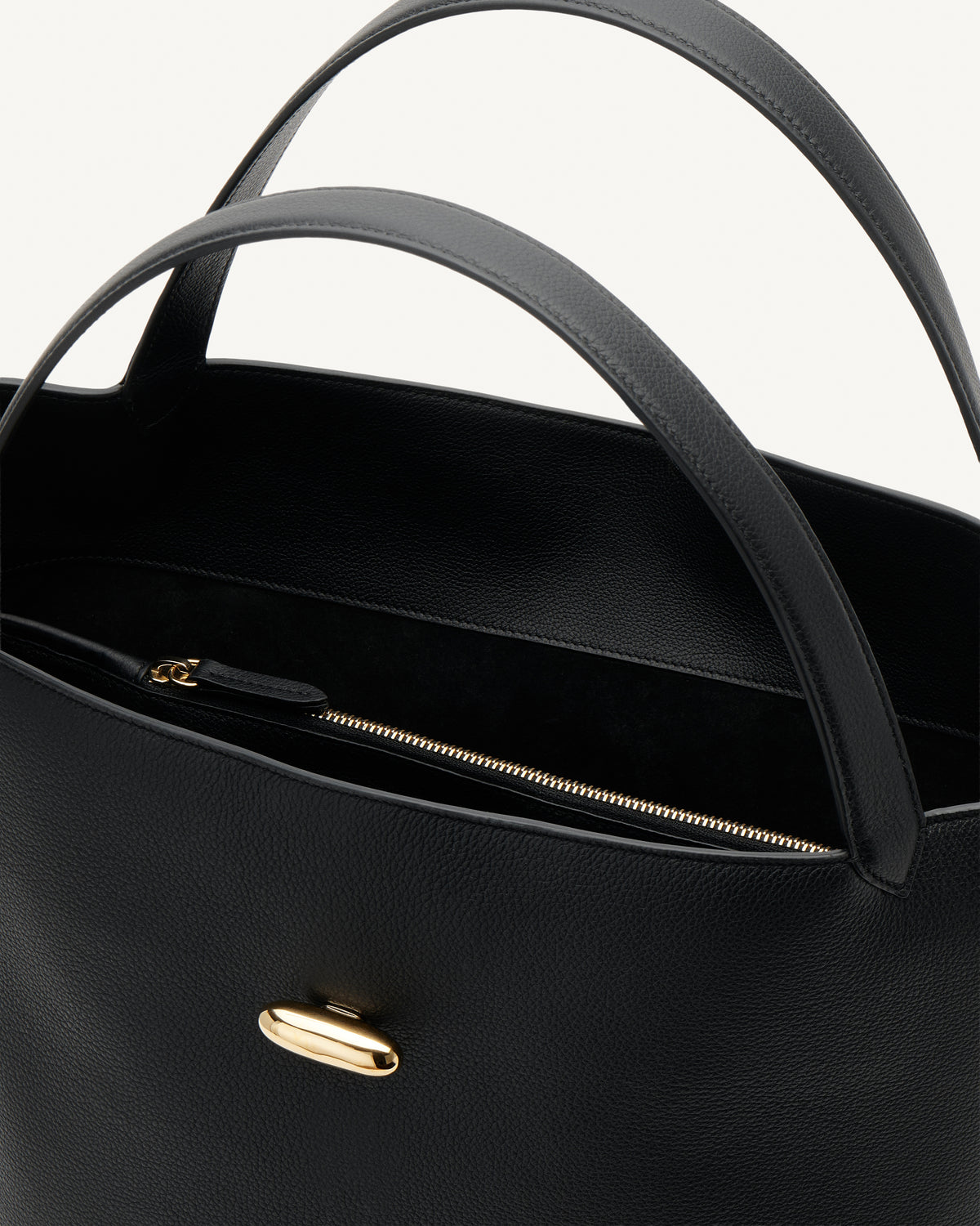 interior view of a black tote bag with gold hardware on a white background