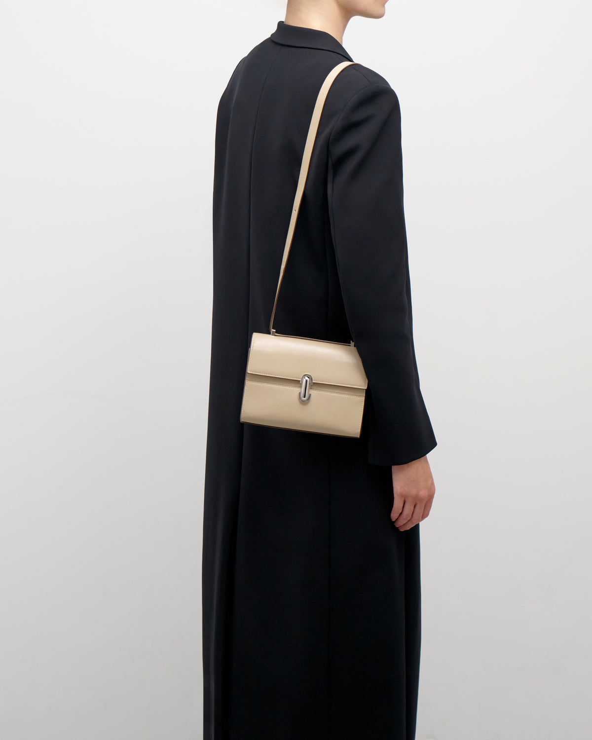 on model view of a bone beige leather bag with a silver clasp on a white background