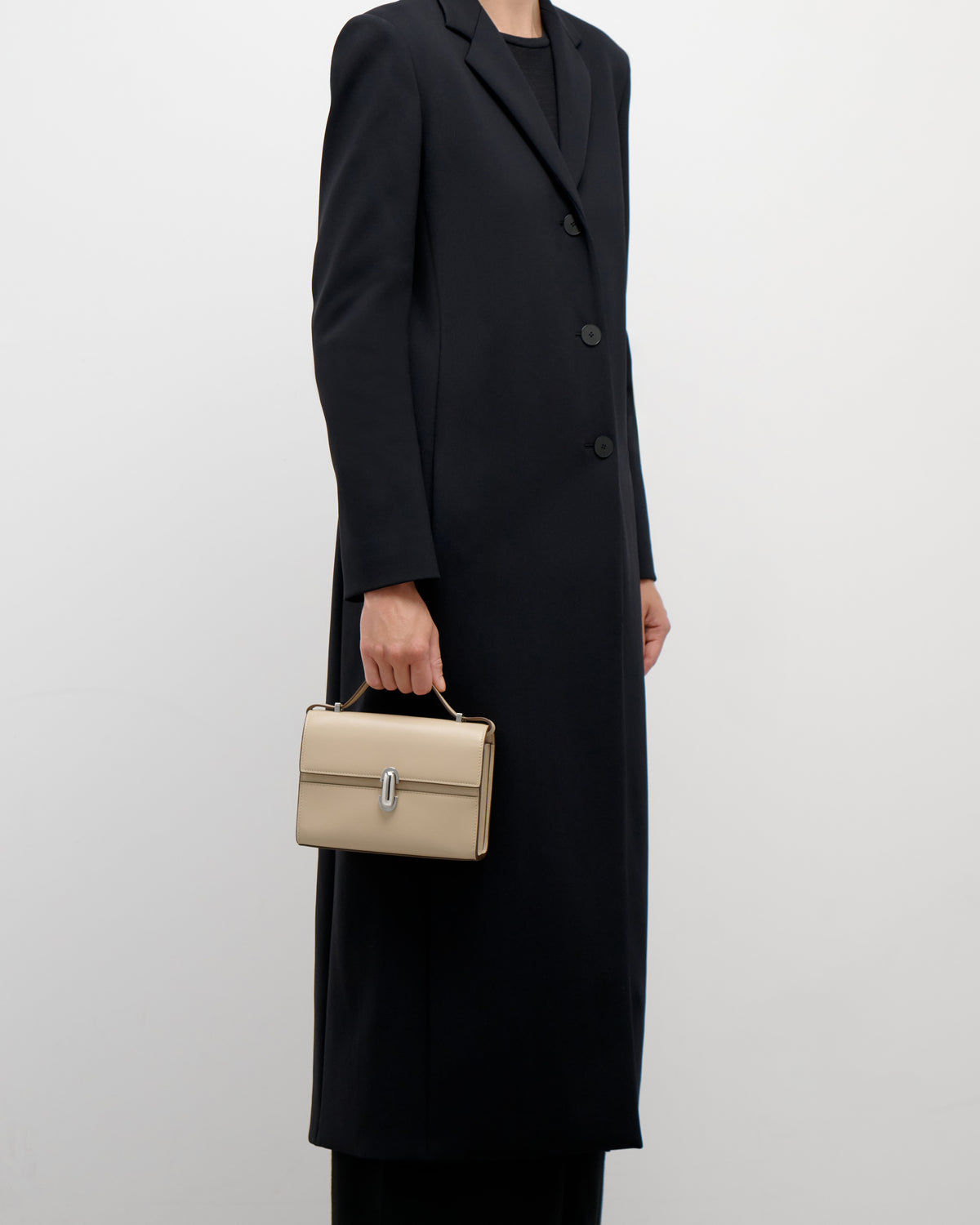 on model view of a bone beige leather bag with a silver clasp on a white background