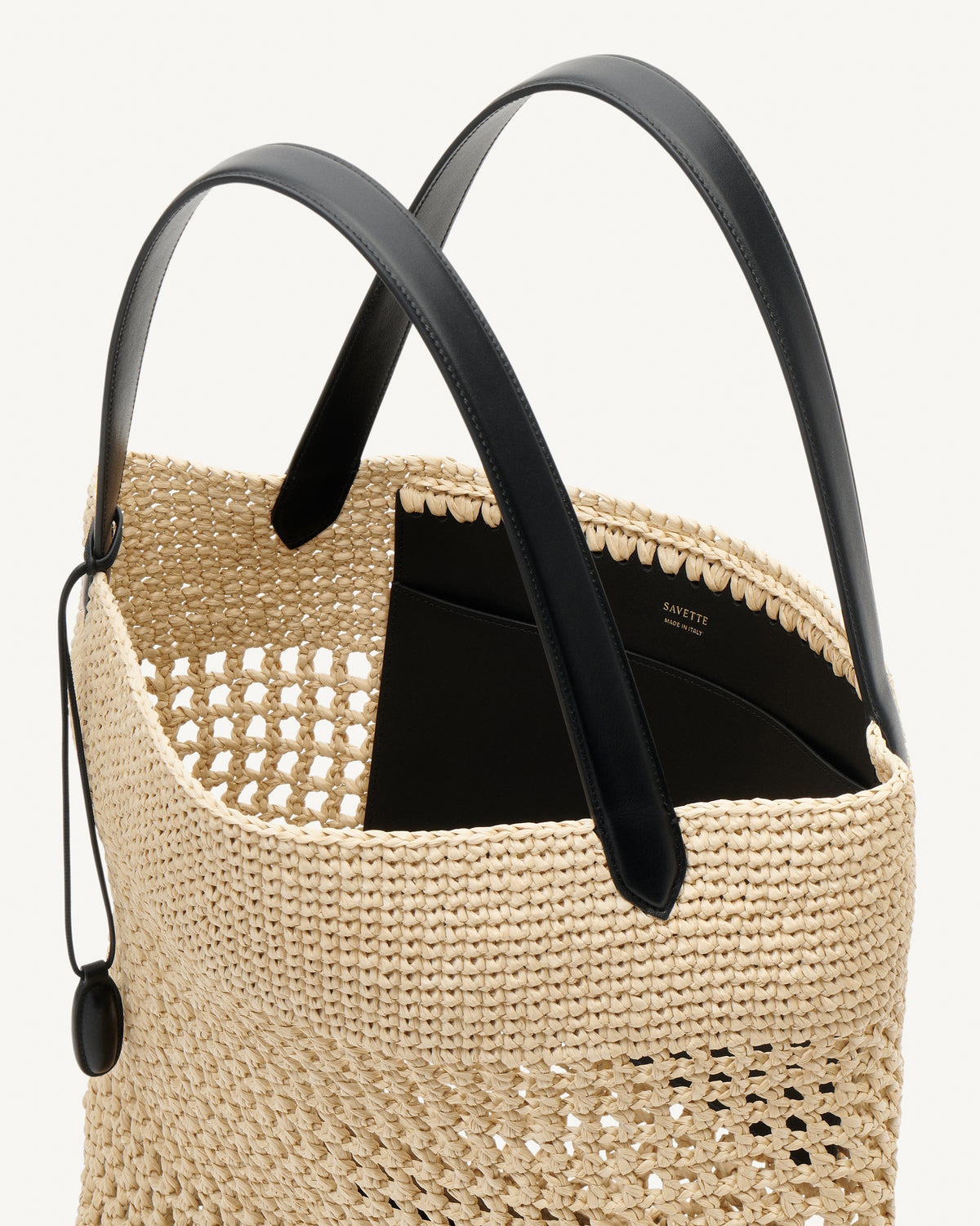 Inside view raffia tote bag with black handle on a white background
