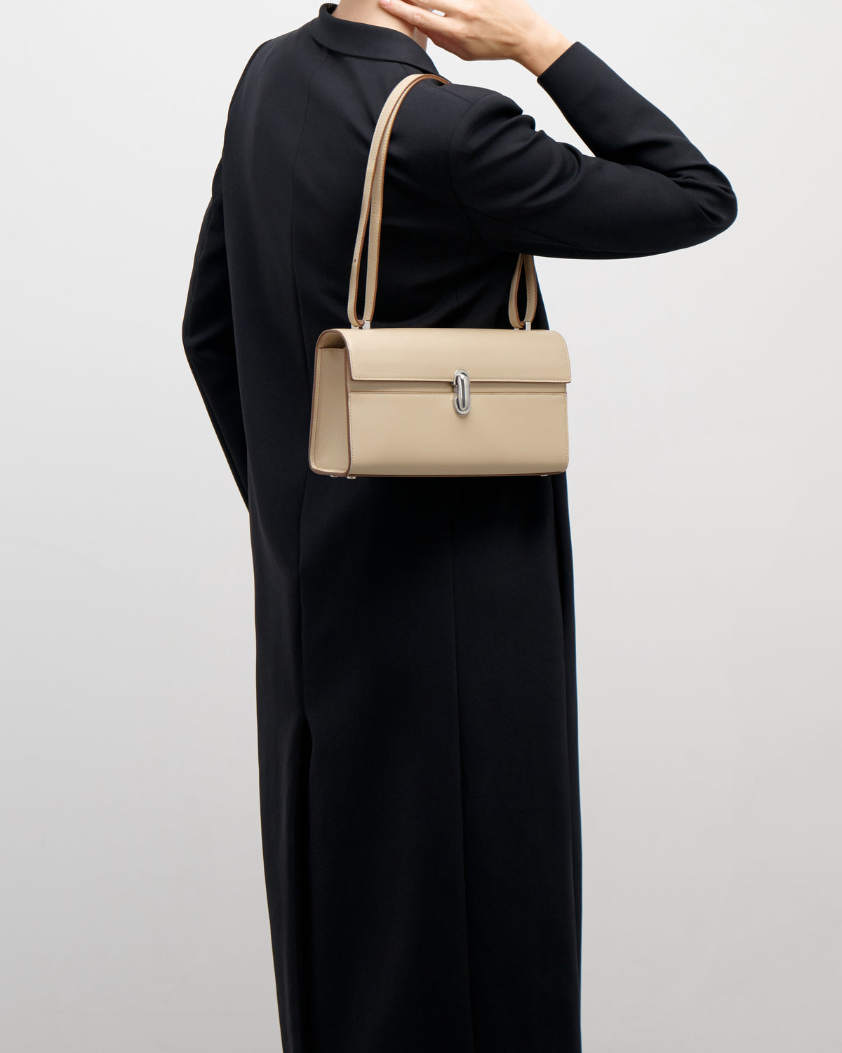 on model view of a bone beige leather bag with a silver clasp on a white background