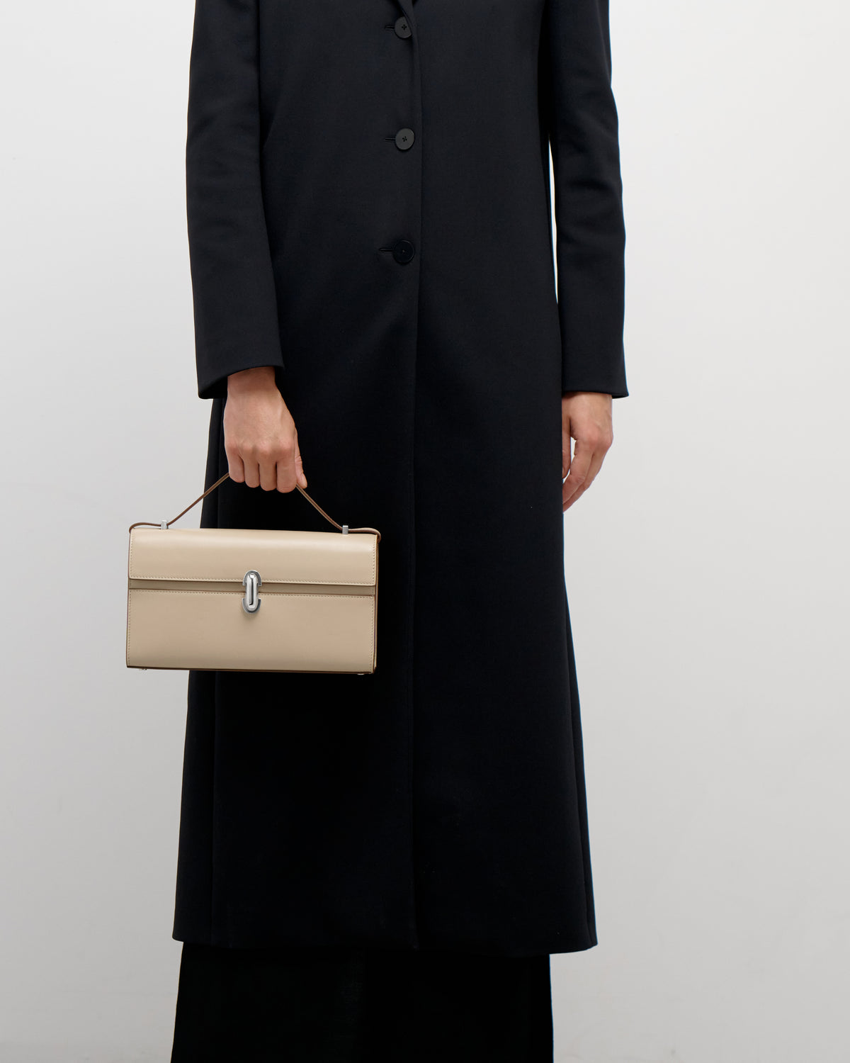 on model view of a bone beige leather bag with a silver clasp on a white background