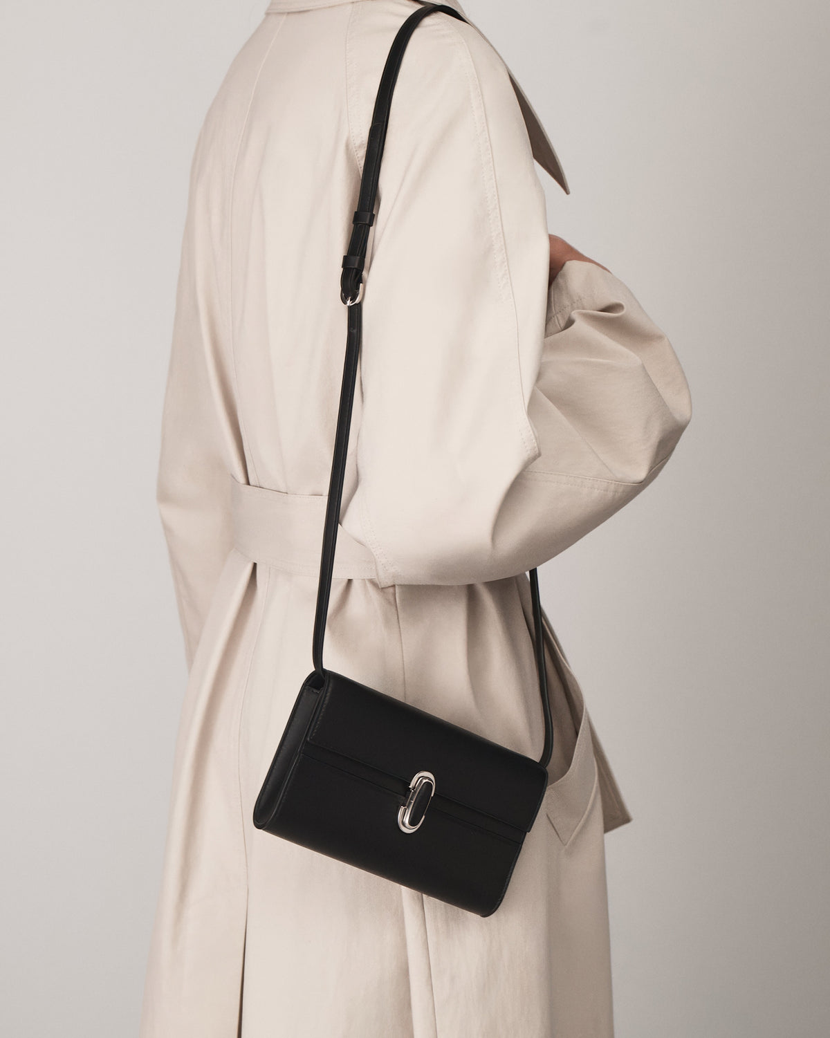 on model view of a black leather handbag with a black leather covered silver clasp on a white background 