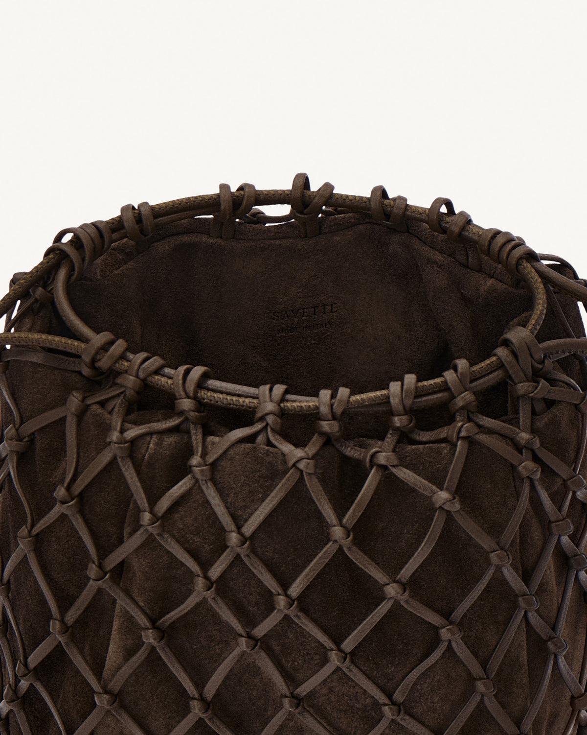 interior view of a coffee brown macrame woven clutch bag with leather drawstring and a gold hardware piece at the bottom on a white background 