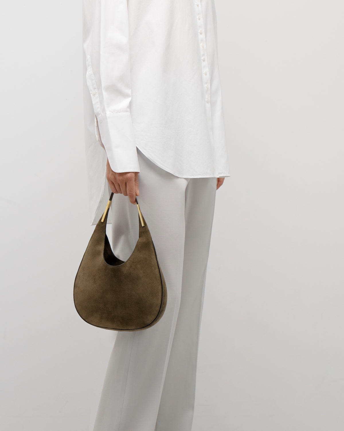 on model view of a mink brown suede bag with gold hardware on a white background