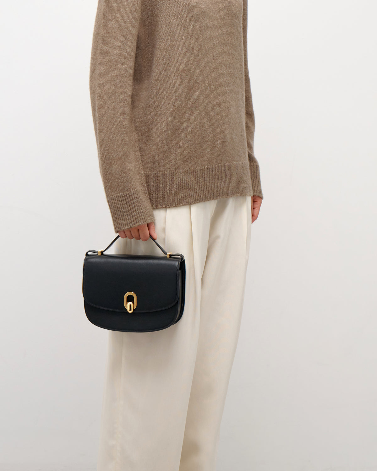 on model image of a black leather bag with gold hardware on a white background
