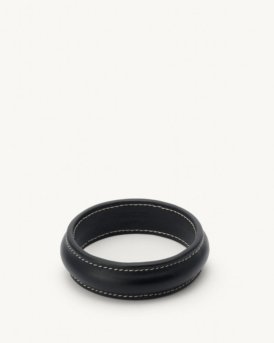 front view of a black leather bangle with white stitching on a white background