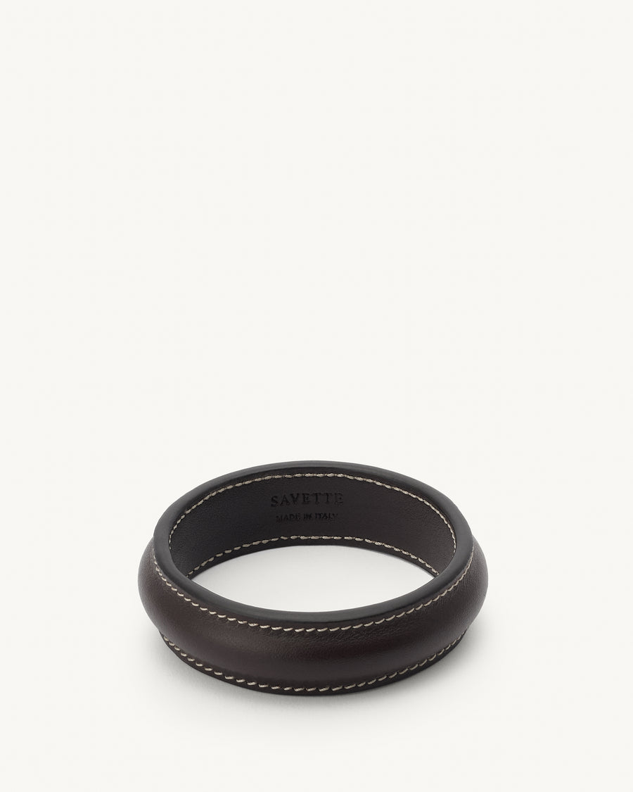 front view of a coffee brown leather bangle with white stitching on a white background 