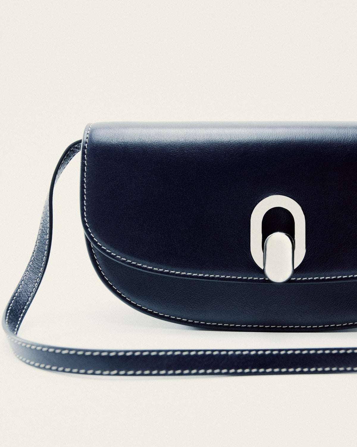 front editorial image of a navy blue bag with a silver clasp on a white background