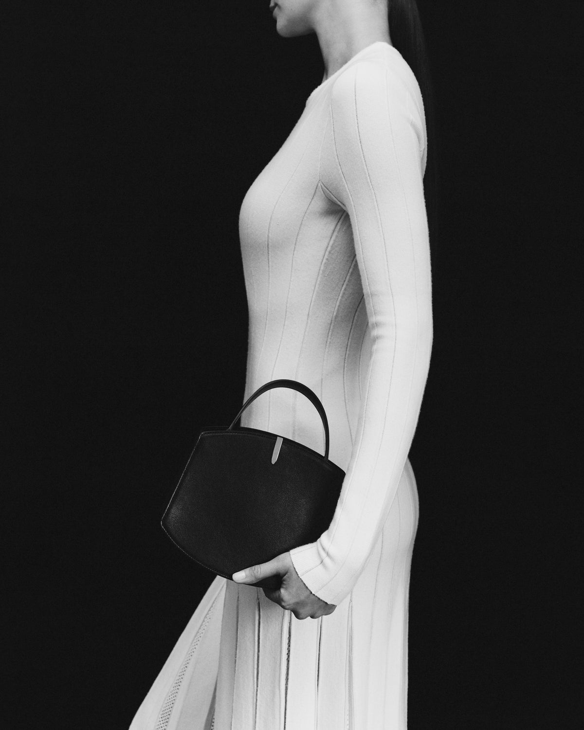 black and white on model image of black bag with silver hardware on a black background