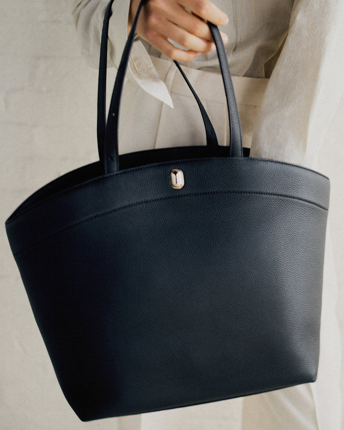campaign on model image of a black tote with gold hardware
